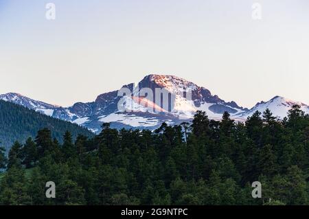 Mountain Peak and Alpenglow at Sunset With Evergreen Forest of Trees in the Foreground Stock Photo