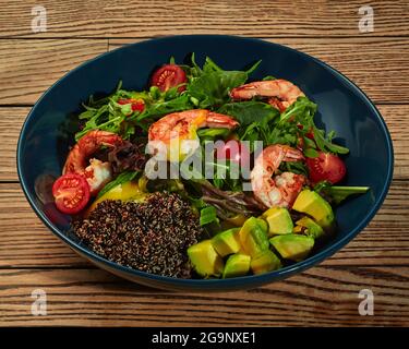Salad with greens, cherry tomatoes, avocado, shrimps and germinated black quinoa seeds Stock Photo