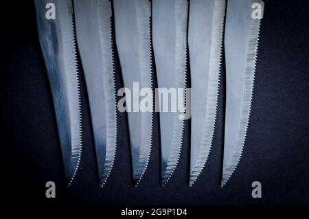 kitchen knife blades on dark gray background, blue toned image, abstract background Stock Photo