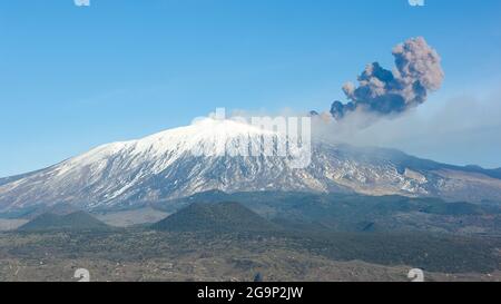 from one side of the volcano Etna rises a tall column of smoke - eruption of 12 genuary 2011 - cooled lava (sciara) flows out Stock Photo