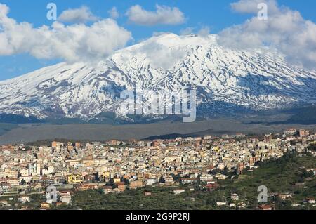 Bronte town under the snowy and majestic volcano Etna and a cloudy blue sky Stock Photo