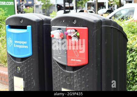 Newspaper and magazines recycling bin and an overflowing cans and plastic bottle recycling bin Stock Photo