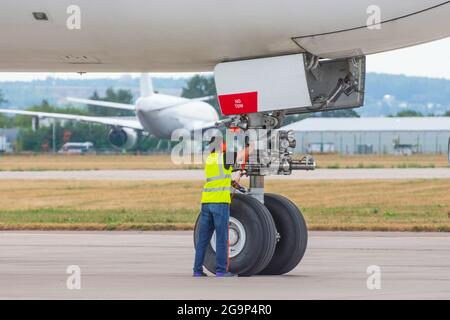 Jet engine aviation technician posing next to a commercial aircraft on the runway Stock Photo