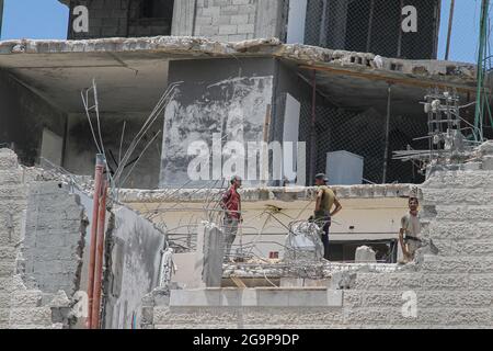 Gaza City. 26th July, 2021. Palestinian workers remove the rubble of a building destroyed by Israeli air strikes in Gaza City, July 26, 2021. TO GO WITH: 'Feature: Gazans suffer from delayed reconstruction after Israel-Hamas fighting in May' Credit: Rizek Abdeljawad/Xinhua/Alamy Live News Stock Photo