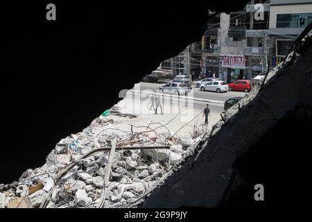 Gaza City. 26th July, 2021. Palestinians walk near the rubble of a building destroyed by Israeli air strikes in Gaza City, July 26, 2021. TO GO WITH: 'Feature: Gazans suffer from delayed reconstruction after Israel-Hamas fighting in May' Credit: Rizek Abdeljawad/Xinhua/Alamy Live News Stock Photo