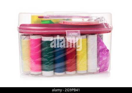 Sewing kit with different spools of thread in a transparent plastic box isolated on a white background Stock Photo