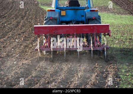 rear closeup view of a articulated tractor with multiple plows that is plowing the earth Stock Photo