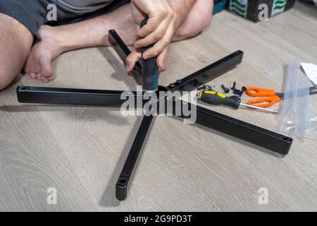 a man assembles a new chair at home. Stock Photo
