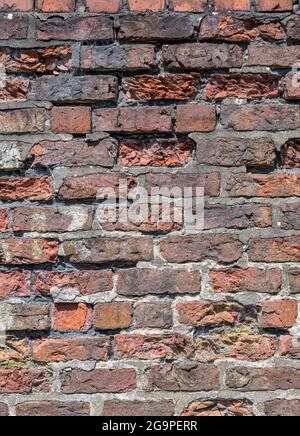 crumbling historic old red brick wall, red brick wall falling down, weathered red brick garden wall, exposed brickwork, brickwork weather beaten damp. Stock Photo
