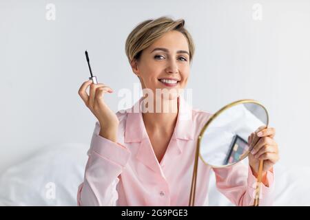 Closeup of smiling woman holding mascara and posing Stock Photo