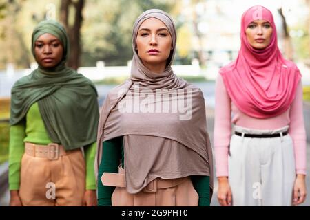 Serious Arab Female Standing In Front Of Diverse Ladies Outside Stock Photo