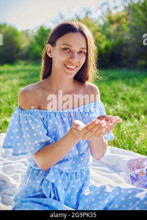Picnic scene: happy smiling girl holds butterfly in hands. Portrait of joyful young woman in the garden Stock Photo