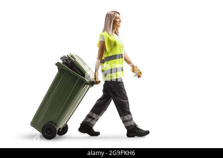 Female waste collector in a uniform and gloves walking and pulling a bin isolated on white background Stock Photo