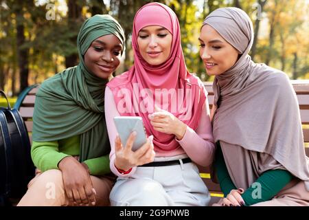 Group Of Muslim Students Women Using Mobile Phone Learning Outdoor Stock Photo