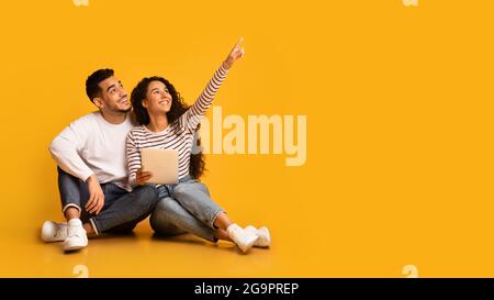 Nice Offer. Excited young arabic couple holding digital tablet and pointing away Stock Photo