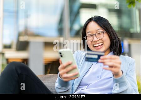 Happy young woman using cell phone to make mobile transaction Stock Photo