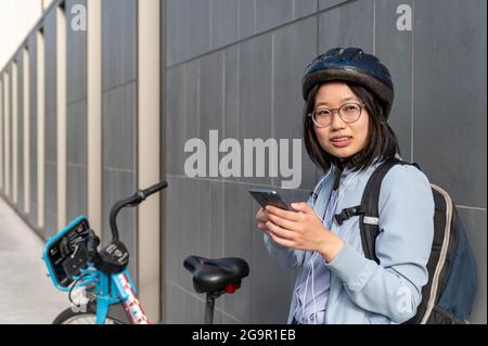 Young woman using cell phone standing next to bike share Stock Photo