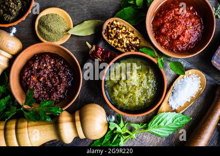 Variety of traditional georgian spices,  sauces and herbs served in ceramic bowls on rustic wooden background Stock Photo