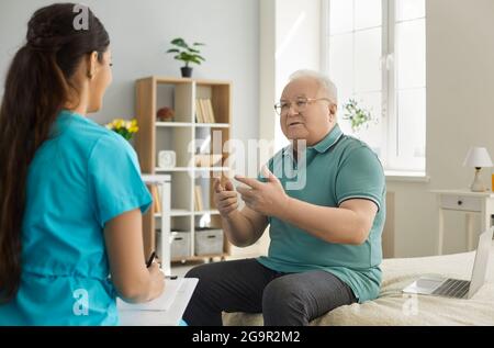 Old man patient talking to doctor with clipboard at planned medical examination Stock Photo