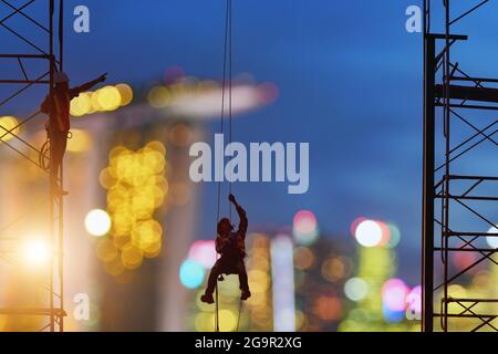 Construction worker wearing safety work at high uniform on scaffolding at construction site on during sunset,working at height equipment. Stock Photo