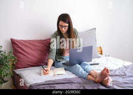 Concentrated young woman freelancer making notes. work from home. Slow life concept. Stock Photo