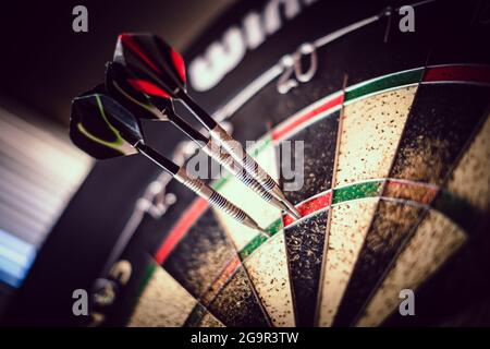 metal-tipped darts stuck in a competition cork dartboard Stock Photo