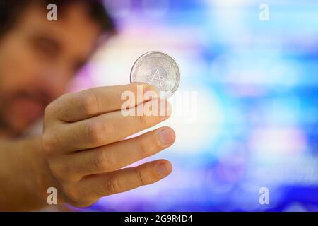 Men holding a Cardano coin, know as ADA coin. Is one of the favorite crypto coins for the future. based on the ethereum cryptocurrency. Cardano logo Stock Photo