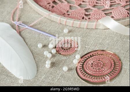 DIY composition of handmade dream cathcer assembling. White feathers, pearls, pink beads and threads Stock Photo