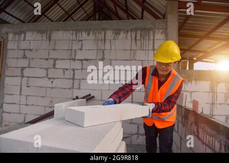 Construction mason worker bricklayer construction worker laying bricks and building barbecue in industrial site,focus on brick ,selective focus Stock Photo