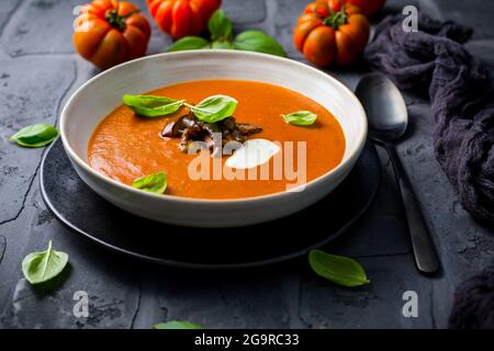 Homemade tomato soup with roasted eggplant and basil on dark background Stock Photo