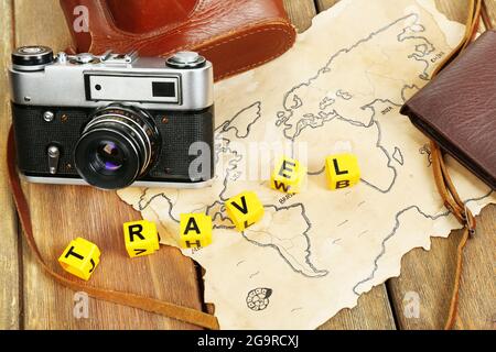 Retro camera on world map with word Travel on wooden table background