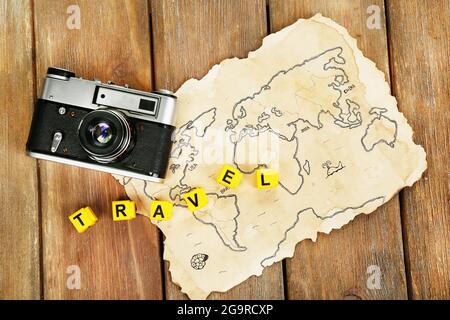 Retro camera on world map with word Travel on wooden table background