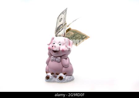 Pink piggy bank in the form of a cute pig and dollar bills. The composition is isolated on a white background. Stock Photo