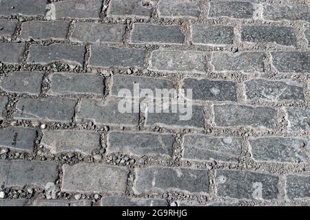 Pattern of old setts or rectangular stone cobbles that formed part of old road surface, St Georges Quay Lancaster visible during road resurfacing work. Stock Photo