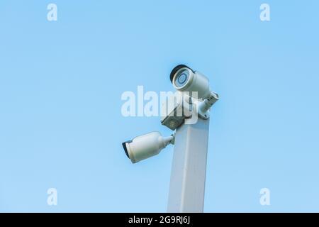 Old security cameras on the gray pole with blue sky on the background Stock Photo