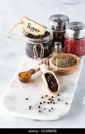 Close up of an arrangement of different types of pepper in various containers on a marble slab. Stock Photo