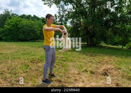 Young Caucasian guy walks and trains his Jack Russell terrier dog in the park Stock Photo