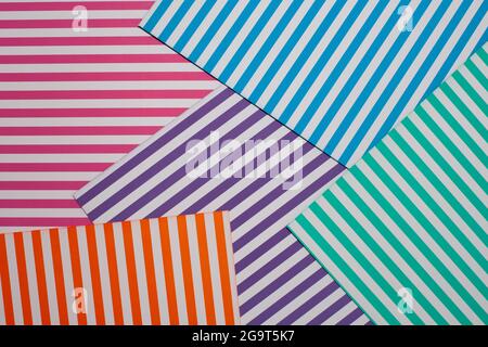Geometric striped background. A modern, trendy multi-colored background made of sheets of striped paper lying in layers on top of each other Stock Photo