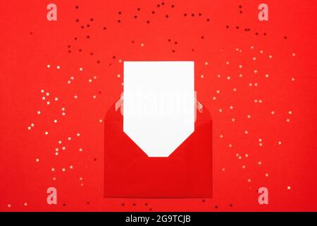 Greeting card for Valentine's day. Red envelope with empty white card on red background. View from above. Holiday or correspondence concept. Place for Stock Photo