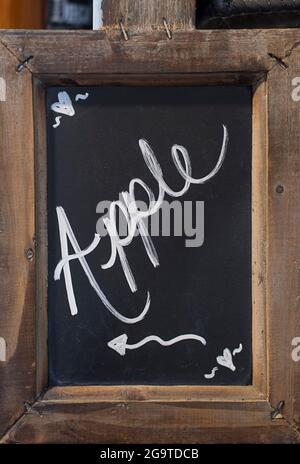 Close-up of blackboard with the hand written word Apple, with an arrow showing to the left, fixed in a wooden rustic frame Stock Photo