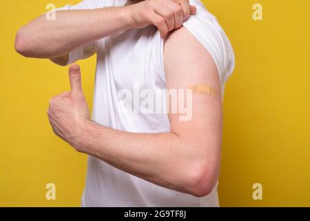 Young man, after getting, receive anti virus vaccine covid-19. Showing arm and thumb up Stock Photo