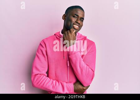 Young african american man wearing gym clothes and using headphones with hand on chin thinking about question, pensive expression. smiling with though Stock Photo
