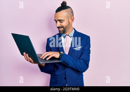 Young hispanic man working using computer laptop looking positive and happy standing and smiling with a confident smile showing teeth Stock Photo