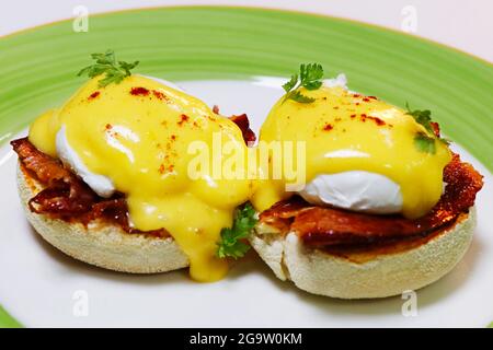 egg benedict on english muffin with pork or beef bacon with rich creamy hollandaise sauce Stock Photo
