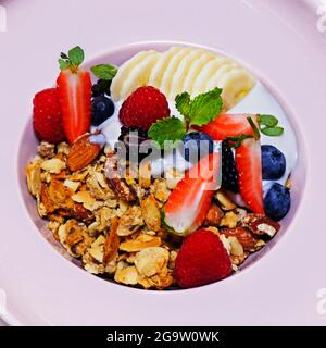 granola bowl with yoghurt, banana and fresh assorted berries. healthy breakfast concept Stock Photo