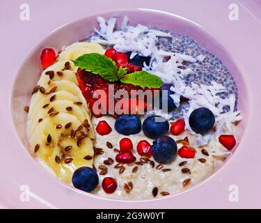 overnight soaked oatmeal and chia bowl with banana, coconut and fresh assorted berries. healthy breakfast concept Stock Photo