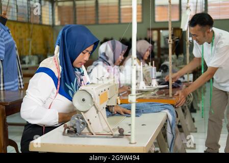 veiled female employees work using sewing machines Stock Photo