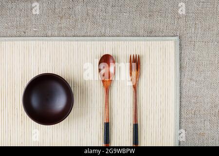 Wooden Spoon, Fork and Plate on a Bamboo Backing. Asian food handicraft concept. View from above Stock Photo