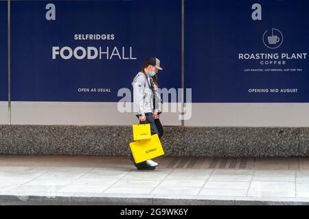 London, UK. 27th July, 2021. People with Selfridges bags walk past the foodhall at their flagship store on Oxford Street.The Iconic department store Selfridges goes on the market with a starting price of £4billion. Selfridge's runs 25 outlets worldwide. Credit: SOPA Images Limited/Alamy Live News Stock Photo