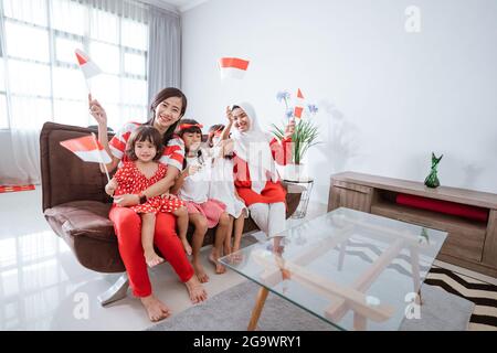 mother and daughter celebrating indonesian independence day at home wearing red and white with indonesia flag Stock Photo